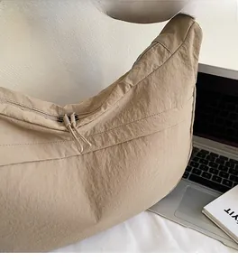 Détail du sac bandoulière beige minimaliste avec double fermeture éclair et tissu en nylon doux