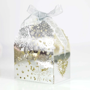 Macro detail of laser-cut silver wedding favor box with intricate floral patterns and ribbon