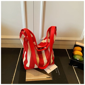 Détail d'un sac cabas en maille rayé rouge et blanc avec anses en similicuir brillant