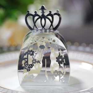 Macro view of silver laser-cut wedding favor box with crown detail and bride groom pattern