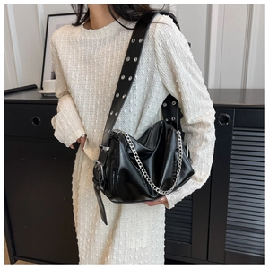 Detail of black glossy crossbody bag with silver metal chain and eyelet wide strap