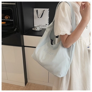 Detail of light blue tote bag showing striped lining and embossed MIVICHI logo detail