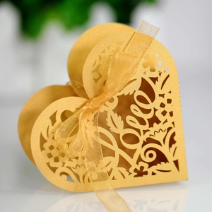 Macro detail of golden laser-cut heart favor box with love lettering and silk ribbon