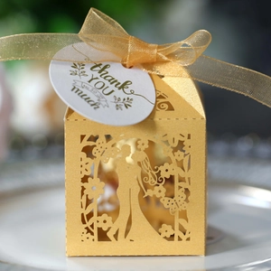 Detail of ivory laser-cut wedding favor box with bride groom design and thank you tag