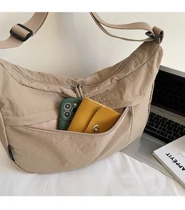Détail d'un sac demi-lune en nylon kaki avec une poche zippée pratique à l'avant pour ranger