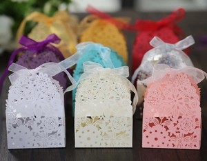 Close-up of laser-cut paper favor boxes in assorted colors with silk ribbon bows