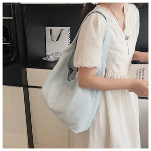 Detail of light blue tote bag showing embossed lettering on soft textured fabric material