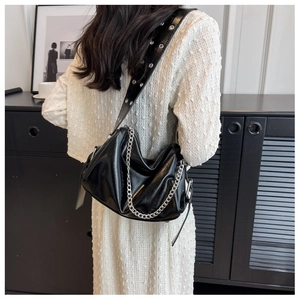 Close-up of black ruched pillow bag featuring bold silver chain and metal eyelet strap