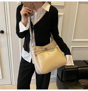 Detail view of large beige leather bucket bag with silver buckle and adjustable strap