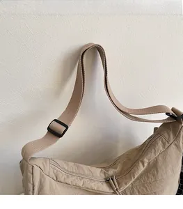 Détail de la bandoulière large réglable et du double zip sur le sac dumpling en nylon kaki