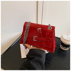 Close-up of glossy red patent leather handbag featuring stylish double buckles and chain strap