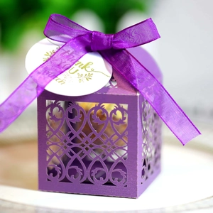 Detail of purple laser-cut wedding favor box with organza bow and Thank You tag