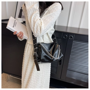 Detail of glossy black pleated tote bag with silver chain and metal eyelet shoulder strap