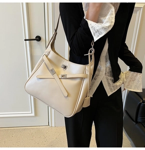 Detail of beige leather bucket bag with silver metal buckle and decorative cross straps