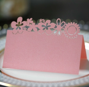 Pink laser-cut floral place card on a dinner plate for elegant wedding table settings