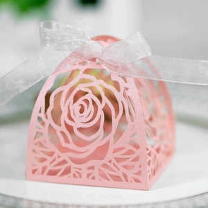 Vista macro di rose tagliate al laser su scatola regalo rosa perlata con nastro d'argento