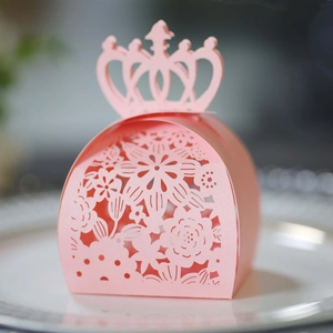 Detailed laser-cut pink favor box with crown top and floral patterns on ceramic plate