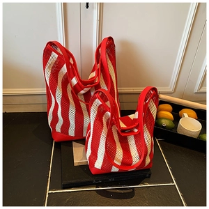 Détail du sac fourre-tout en mesh rayé rouge et blanc avec anses en similicuir renforcé