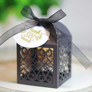 Macro view of black laser-cut gift box with sheer ribbon and Thank You gold tag