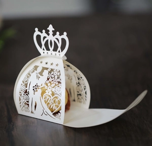 Laser-cut white wedding favor box featuring crown and Mr & Mrs silhouette on wood
