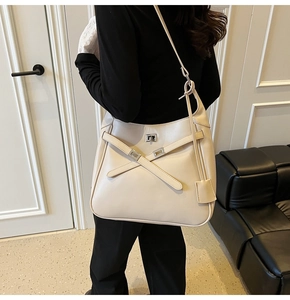 Close-up of beige leather hobo bag with criss-cross straps and silver metal swivel lock