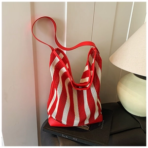 Détail du sac cabas en maille à rayures rouges et blanches avec coins en cuir rouge