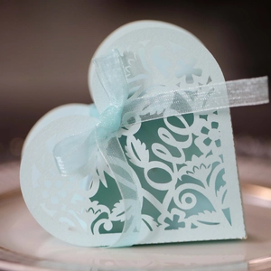 Detail of light blue heart-shaped laser cut wedding favor box with Love text and ribbon