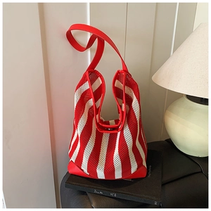 Détail de la texture en maille rayée rouge et blanc et de la bandoulière en cuir du sac cabas