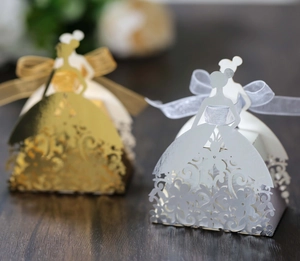 Close-up of laser-cut wedding favor boxes in bride dress shape with ribbons