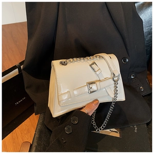 Close-up of cream PU leather crossbody bag with silver chain strap and buckle detail