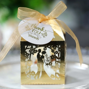 Macro shot of ivory laser-cut candy box with mirror gold finish and thank you tag