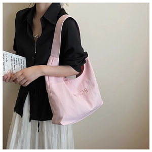 Detailed view of pink nylon tote bag with AMVICHI embroidery shown on a model