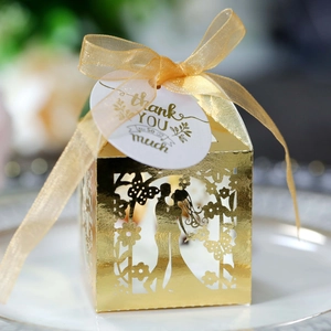 Close-up of ivory laser cut wedding favor box with bride groom pattern and thank you tag
