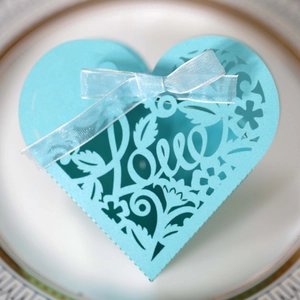 Close-up of light blue laser-cut heart favor box with Love text and ribbon bow