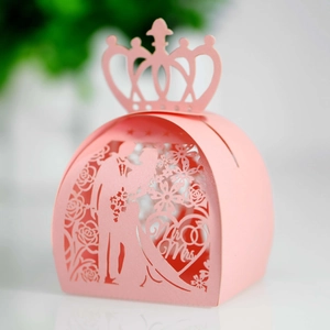 Macro shot of pink laser-cut wedding favor box featuring bride and groom silhouettes