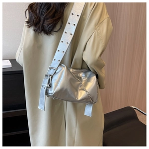 Detail of silver metallic shoulder bag with metal eyelets on wide strap and chain detail