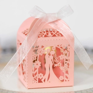 Detailed laser-cut pink wedding favor box with silhouette of a couple and white ribbon bow