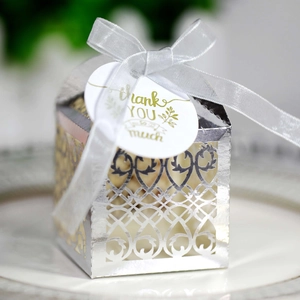 Detail of silver laser-cut heart favor box with white ribbon and Thank You gold tag