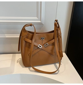 Detailed view of brown leather tote bag with silver buckles and cross strap design