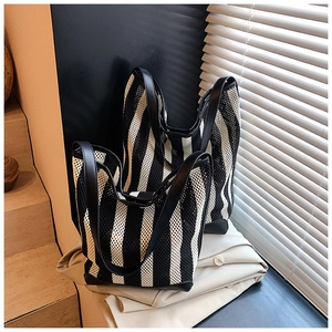 Détail du sac cabas en maille rayée noire et blanche avec poignées en cuir élégantes
