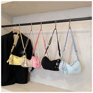 Five assorted colors of nylon half-moon crossbody bags on a display rack with accessories