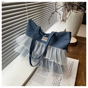 Detail of blue denim tote bag featuring white lace ruffles and Fashion Bag patch