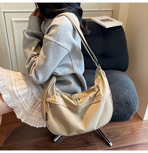 Vue macro du sac hobo beige montrant la texture en nylon et la bandoulière réglable
