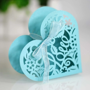 Detail of light blue laser-cut heart favor box with Love script and ribbon bow