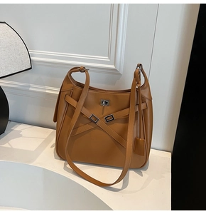 Detailed shot of caramel brown leather bucket bag with silver twist lock and strap
