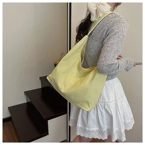 Model wearing a large yellow canvas tote bag with MIVICHI embroidery on stairs