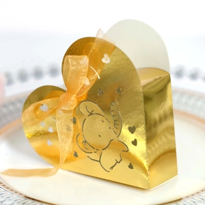 Dettaglio macro di una scatola di caramelle dorata a forma di cuore con elefante e nastro giallo