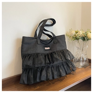 Close-up of black denim tote bag with sheer organza ruffles and Fashion Bag label