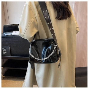 Detail of black crossbody pillow bag with silver chain and metal eyelet wide strap
