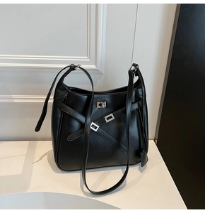Detail of a black leather bucket bag featuring silver buckle and cross strap design